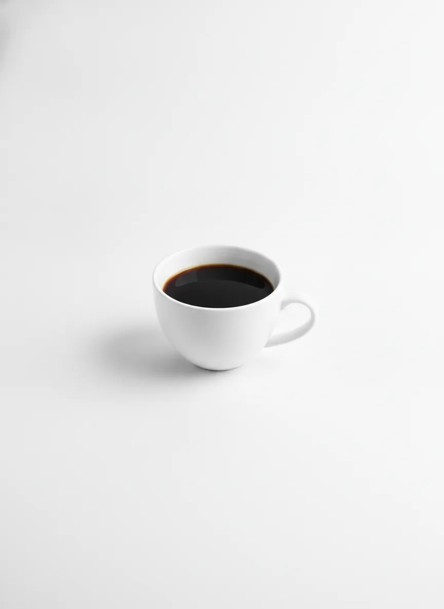 A single white cup of black coffee photographed square-on against a bright neutral seamless background, high-key and shadowless