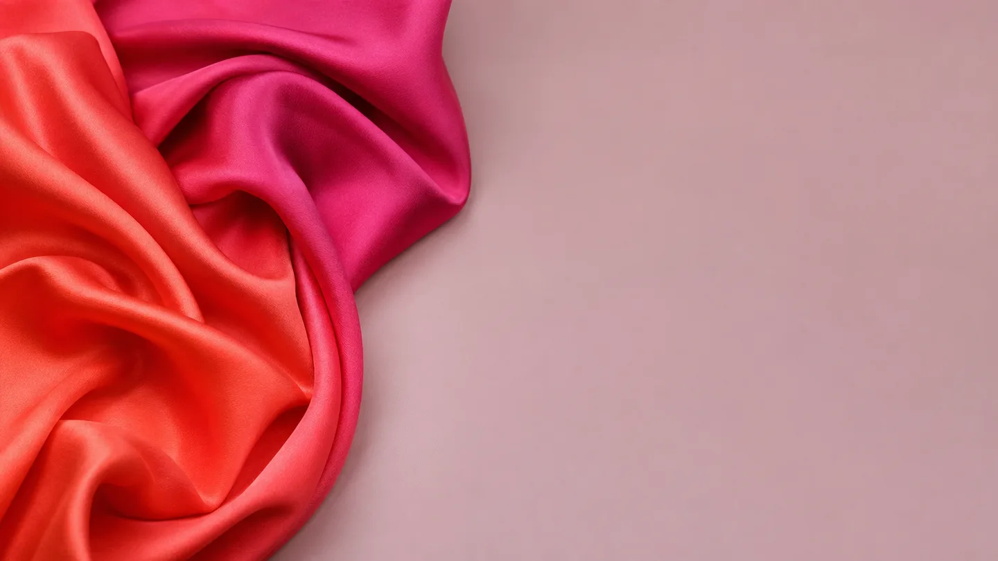 A length of coral-into-magenta silk, folded and lit softly
