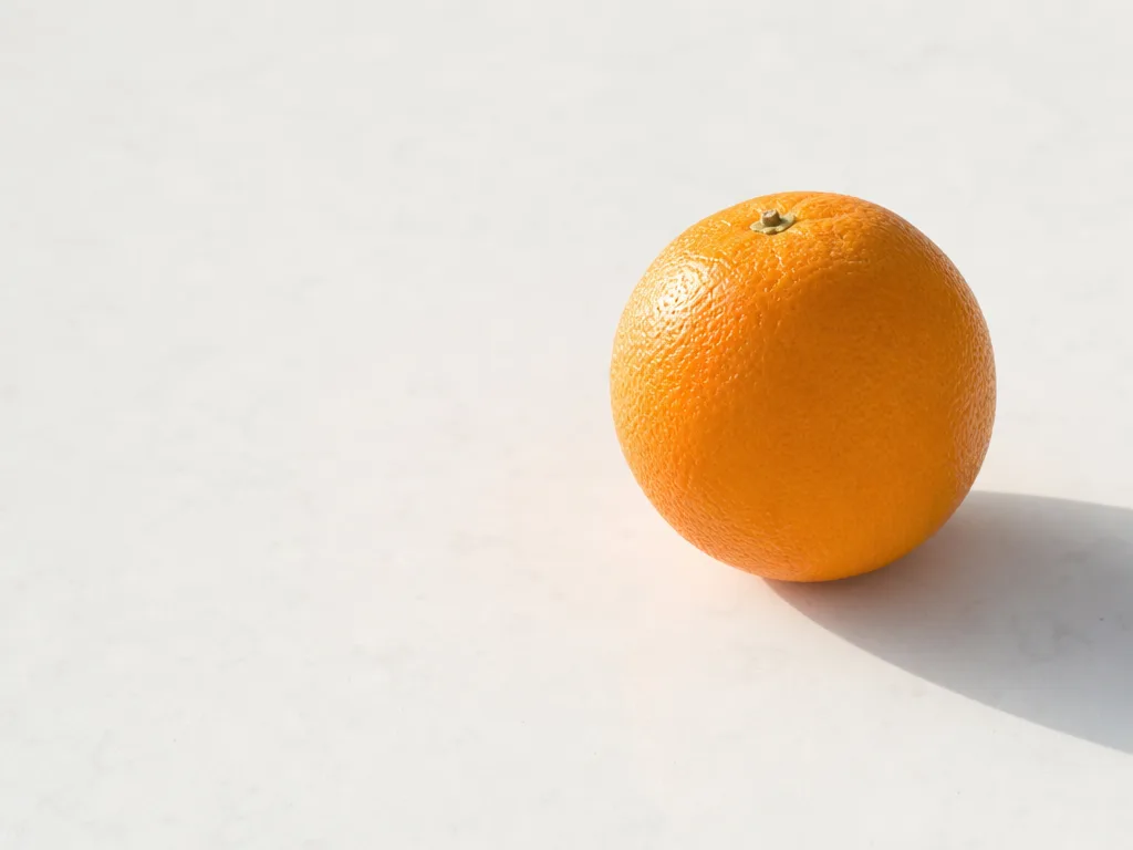 A single bright piece of citrus fruit on a clean pale surface — a sample render served by Refract.